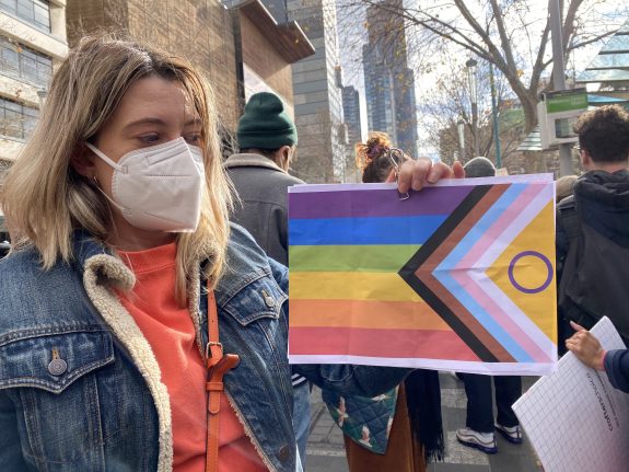 woman holds LGBTQI+ flag at Roe Overturned rally